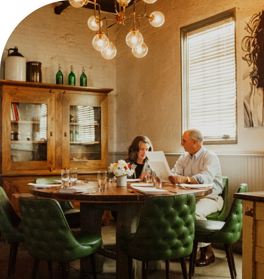 Round dining table with green chairs and two patrons