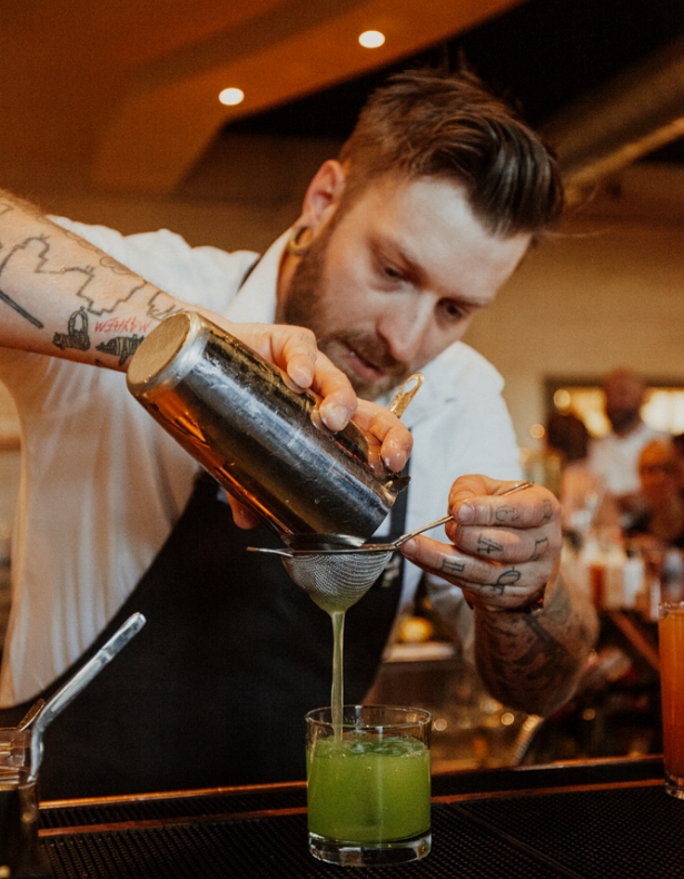 Clay Pigeon's bartender pouring a green drink